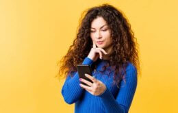 Mulher de azul olhando para o celular e descobrindo O que fazer para ganhar dinheiro rápido